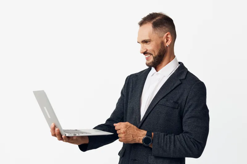 A professional business man holds a laptop against a solid colored background, exuding confidence, focus, and composure in a polished corporate portrait suitable for business and tech topics.