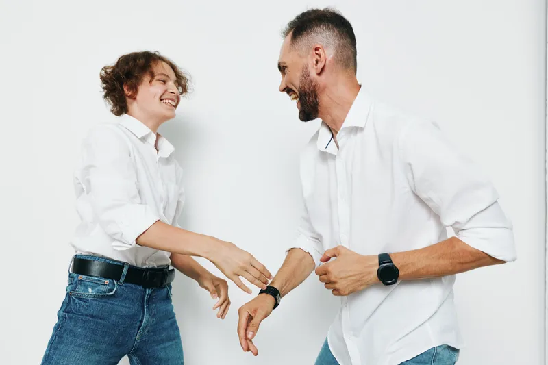 A professional man and colleague share a confident, joyful moment on a solid colored studio background, isolated and clean, expressing optimism, energy, and forward momentum.