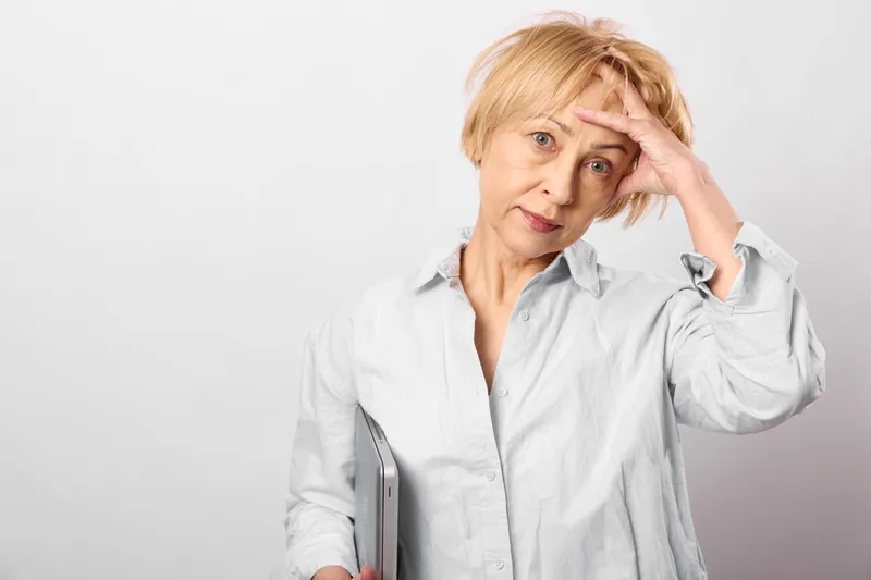 Woman stress healthcare burnout mental health doctor headache fatigue elderly, in white coat, hand on forehead, worried tired face, concept burnout and anxiety in healthcare, studio background