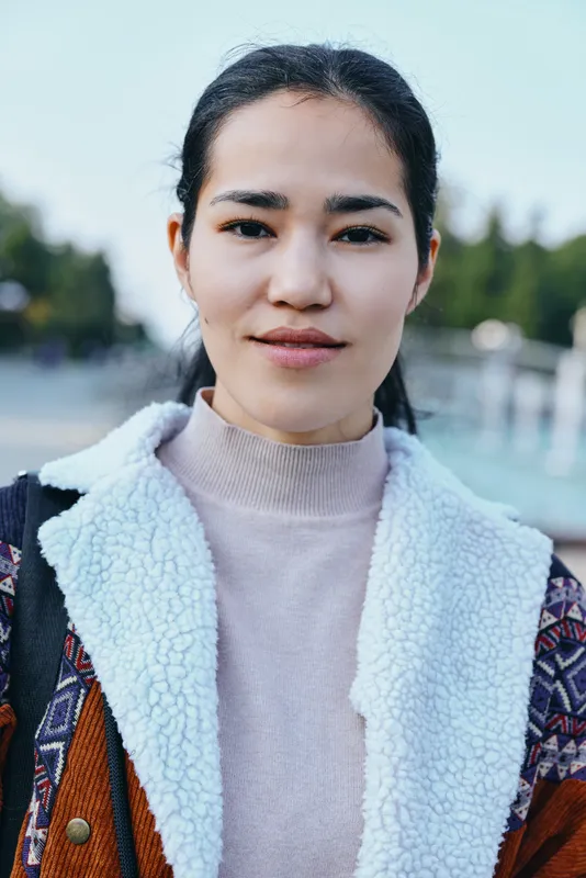 Close up of a woman outdoors wearing a cozy fleece lined jacket and knit sweater, calm expression, natural light, street style mood, versatile for fashion and lifestyle photography