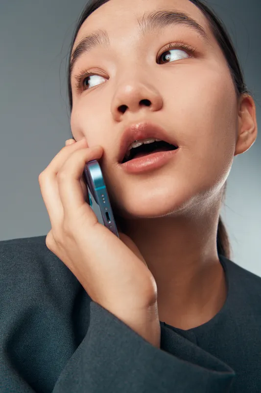 Woman talking on smartphone with thoughtful expression and hand near cheek in closeup portrait. Female person communicating, technology use, communication concept with modern device.