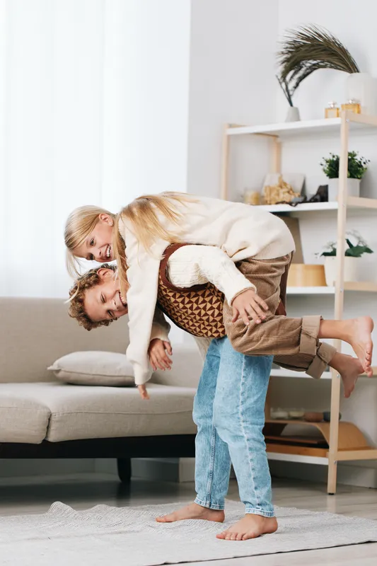 Authentic playful moment featuring a parent and child in a game, showcasing lifestyle warmth, genuine interaction, laughter, and movement in a cozy home setting.