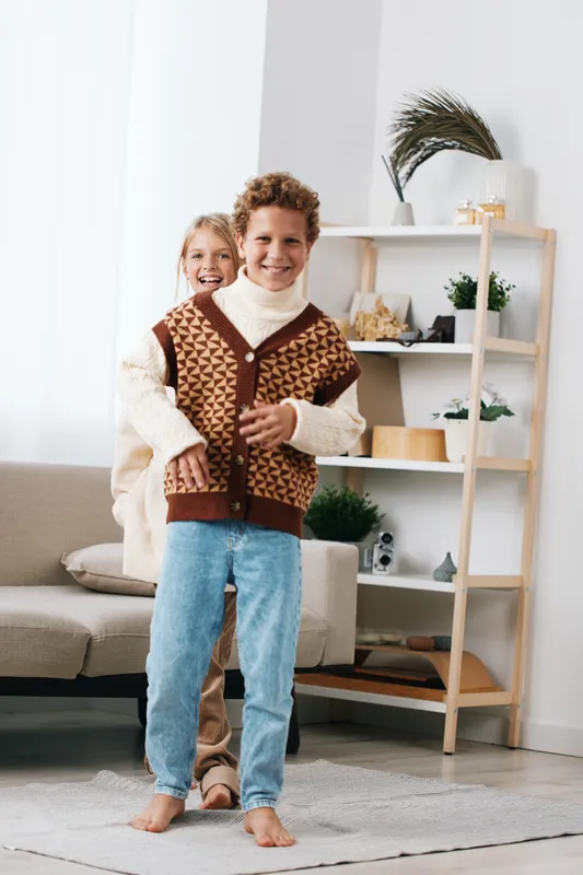 Authentic candid scene of playful children indoors, showcasing a school inspired lifestyle with cozy knitwear and simple games, capturing genuine energy and cheerful charm.