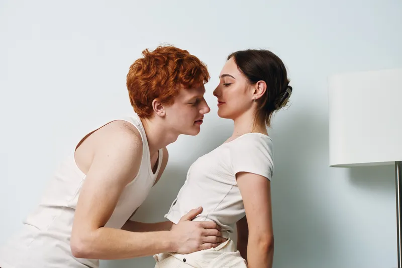 Couple in casual clothes leaning close for romantic moment, young man and woman with affection and tenderness in indoor setting, love and connection feeling