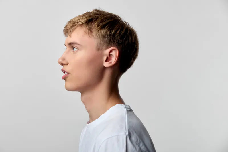 Profile of a young man in a plain white tee, side view against a neutral backdrop, calm expression and clean studio lighting for a minimalist, versatile image