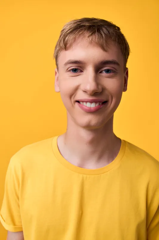 Young smiling male in a yellow t shirt against a bright studio background, conveying casual style, warmth, optimism and a friendly vibe for stock photography and lifestyle projects