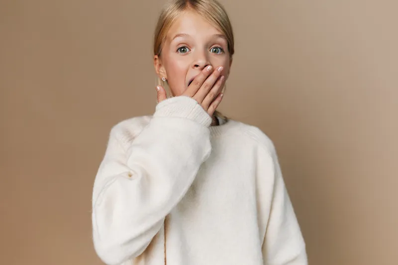 Authenticity shines in a candid portrait capturing a youthful moment of play and everyday lifestyle, featuring a cozy sweater and a soft, neutral setting that feels real.