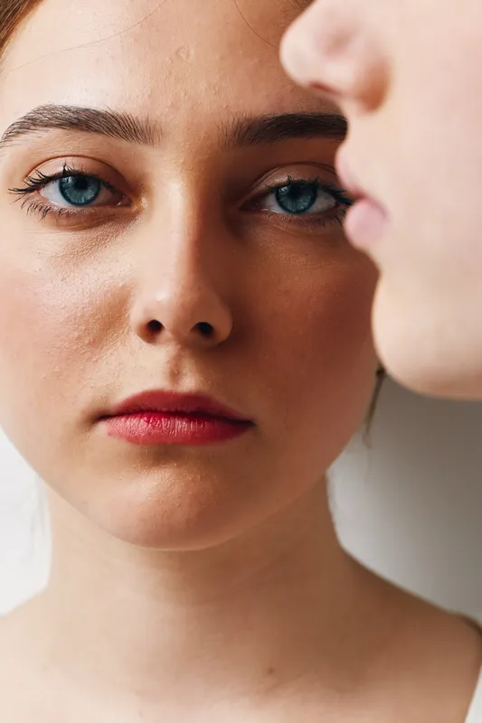 Portrait of young woman with blue eyes and natural makeup looking at camera with serious expression, closeup face and clear skin on neutral background.
