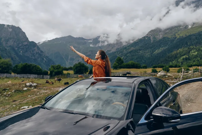woman in car sunroof mountains travel authenticity