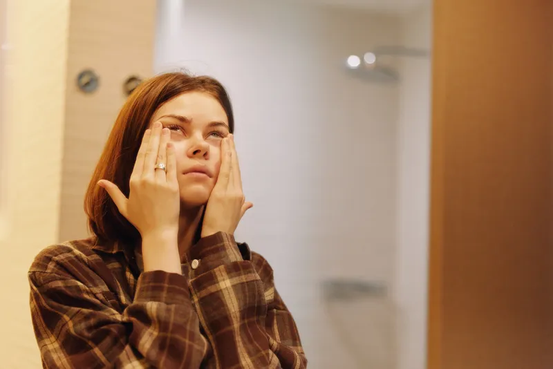 woman skincare facial bathroom routine selfcare, closeup of face with hands applying moisturizer, warm light, mirror reflection, calm personal care moment