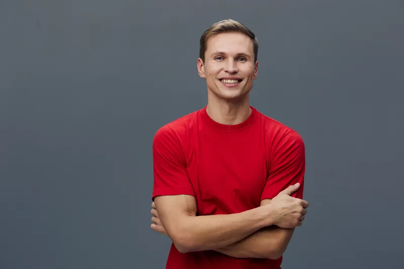 Smiling man wearing red t-shirt crossed arms standing isolated gray background digital nomad lifestyle concept