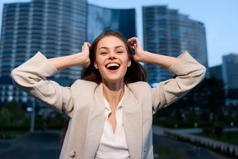 happy woman laughing outdoors in white jacket with modern buildings background city lifestyle business concept