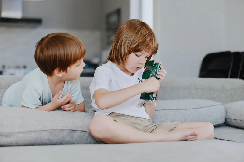 Two children playing joyfully with toy cars in a cozy, modern living room, highlighting creativity and imagination during playtime.