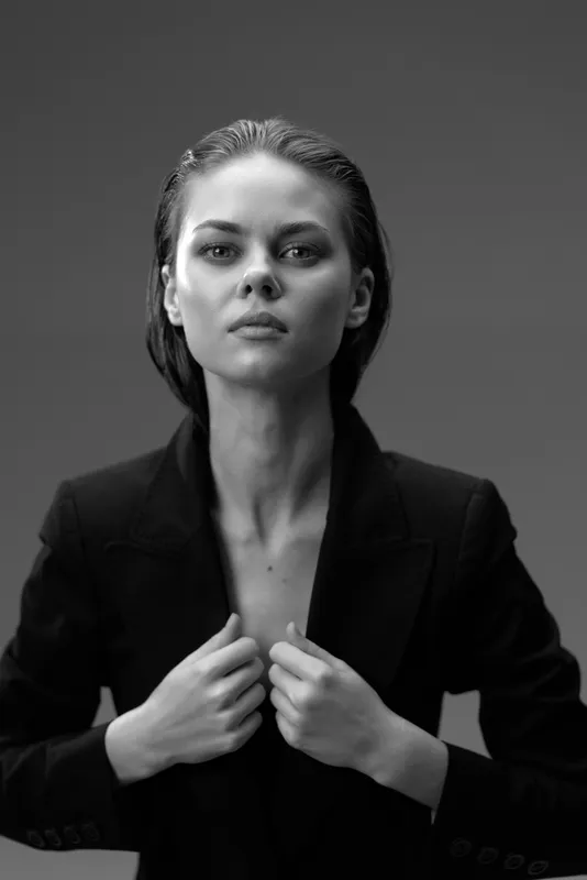 Black and white portrait of confident woman in blazer with serious expression and slicked-back hair