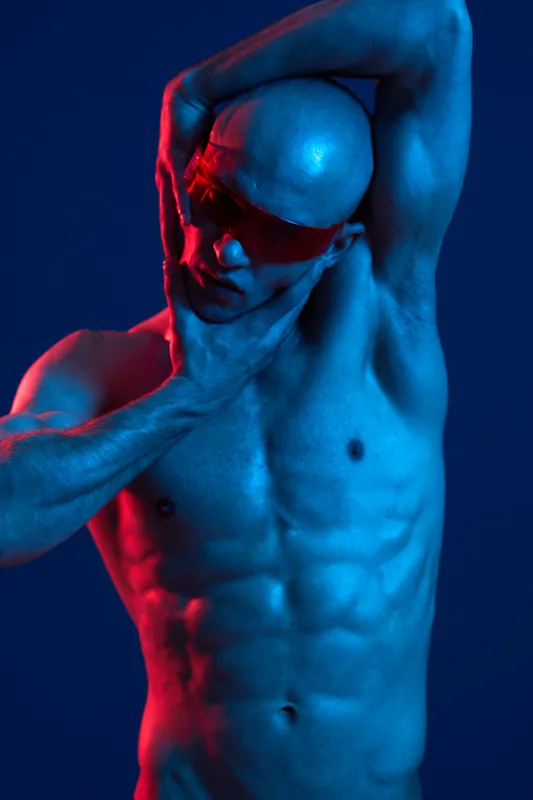 Artistic portrait of a man in vibrant lighting, showcasing his muscular physique and unique pose. Captivating and striking, perfect for creative projects.