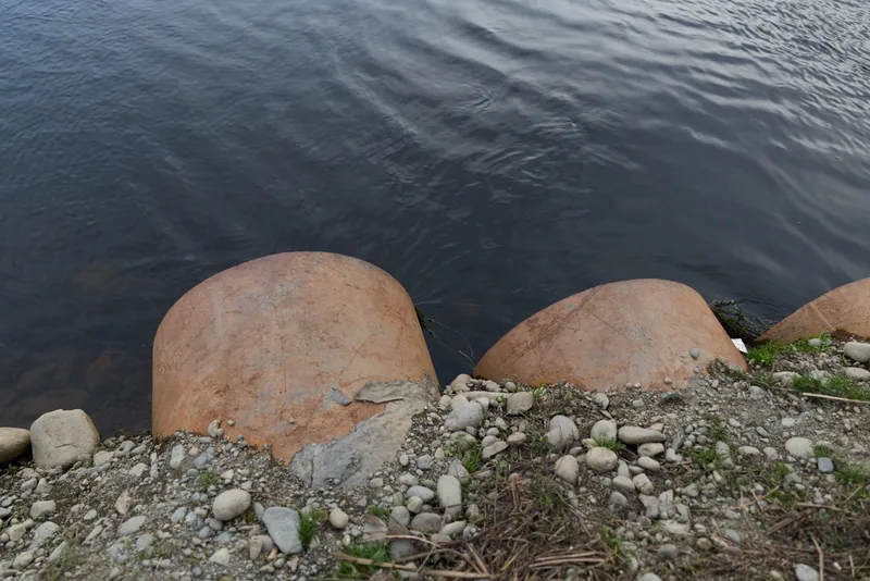 Shoreline water with smooth rocks and scattered pebbles, natural outdoor landscape, calm ripples and stone textures, relaxed lifestyle mood, summer lakeside scene, soft daylight