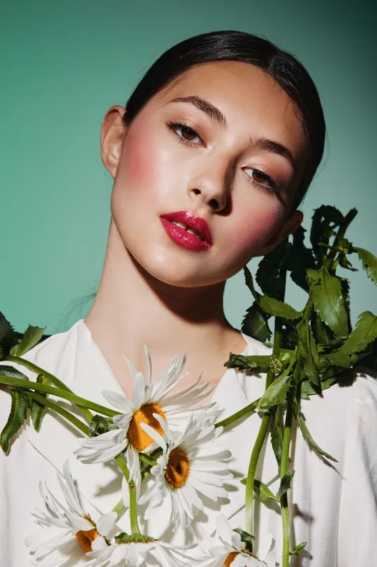 Close-up portrait of young woman with creative fashion makeup wearing floral accessories. Concept of beauty, artistic style, fresh elegance and trendy beauty culture.
