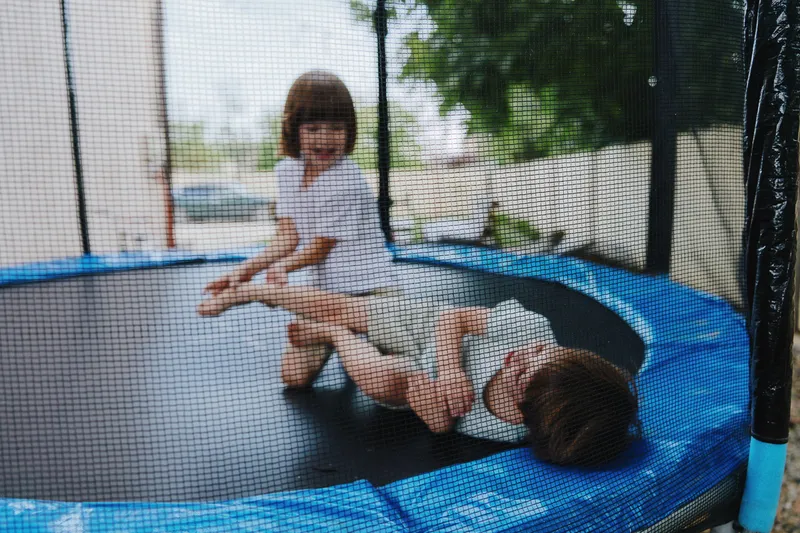 Happy children playing together on a trampoline, enjoying laughter and fun moments in the sun. Their cheerful expressions create a vibrant atmosphere. ###