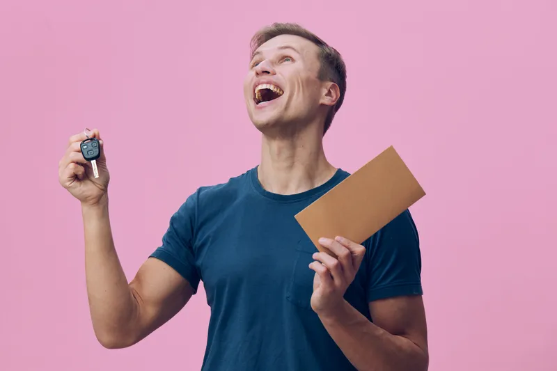 cheerful man holding car key and envelope excited look pink background digital detox concept technology freedom happiness