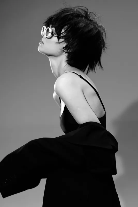 Black and white portrait of a stylish woman in sunglasses and elegant outfit showing confidence and modern fashion.