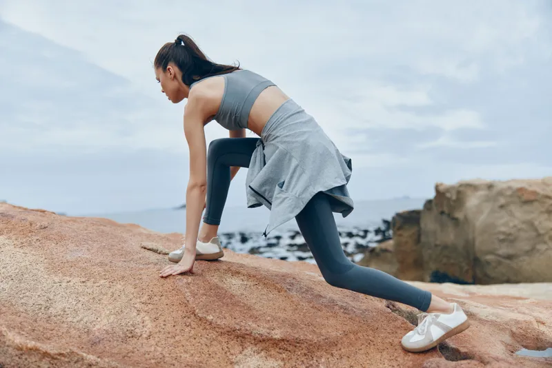 Athletic young woman engaged in outdoor workout on rocky terrain, wearing stylish activewear, showcasing determination and fitness lifestyle