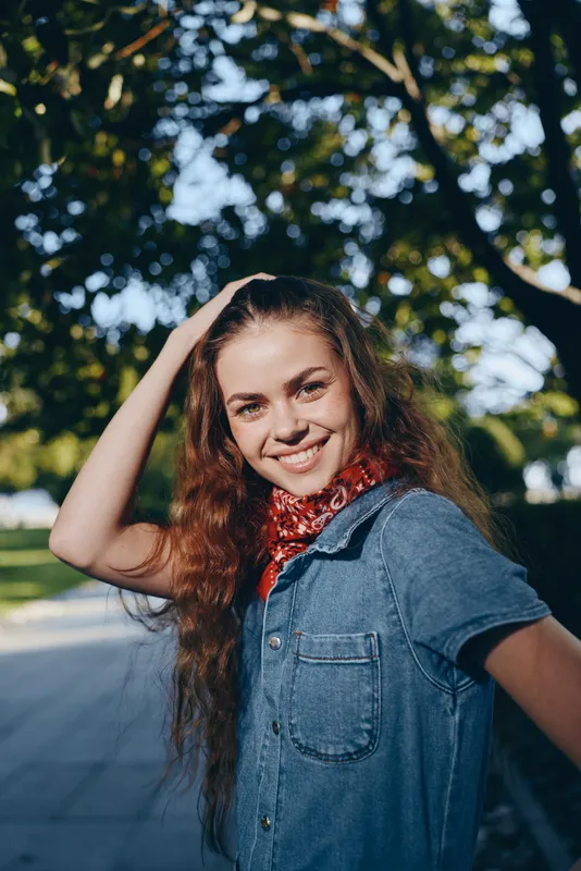 smiling woman in modern boho-western denim street style with film color effect, casual outfit, outdoor, natural sunlight, relaxed mood, lifestyle portrait