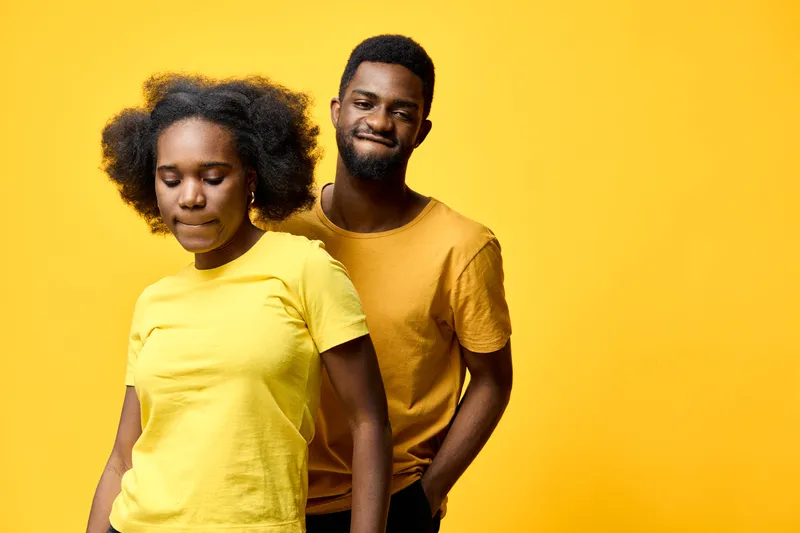 Young couple posing in matching yellow outfits against a vibrant yellow background, conveying joy and harmony in a cheerful, seasonal setting