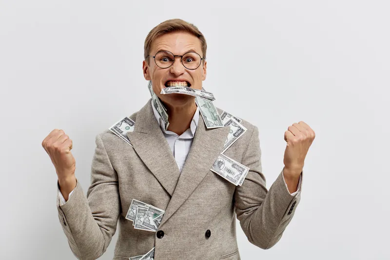 excited young caucasian man wearing plaid blazer biting money cash celebrate success isolated on grey background financial freedom concept