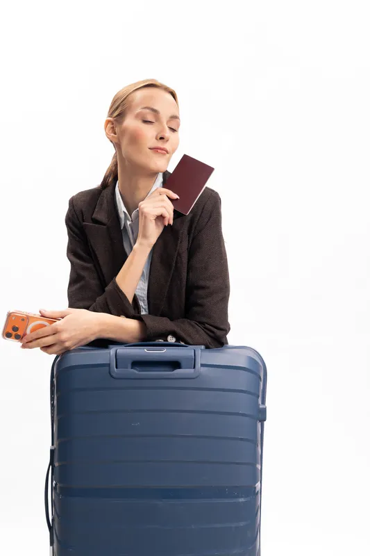 Young woman with suitcase holds passport and phone, ready for travel. Isolated on white background. Concept of vacation, journey, and trip preparation.