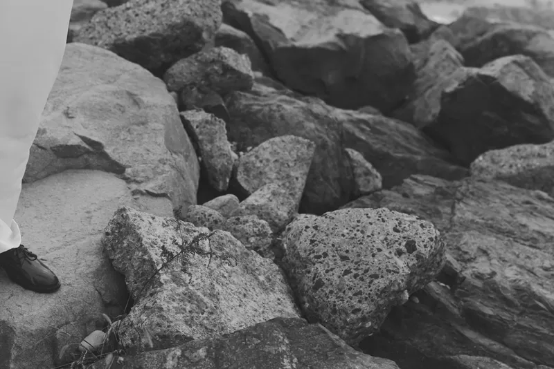 Rugged rocks and a booted foot stepping on uneven terrain, an outdoor scene highlighting footing, balance, and the rough texture of natural stone