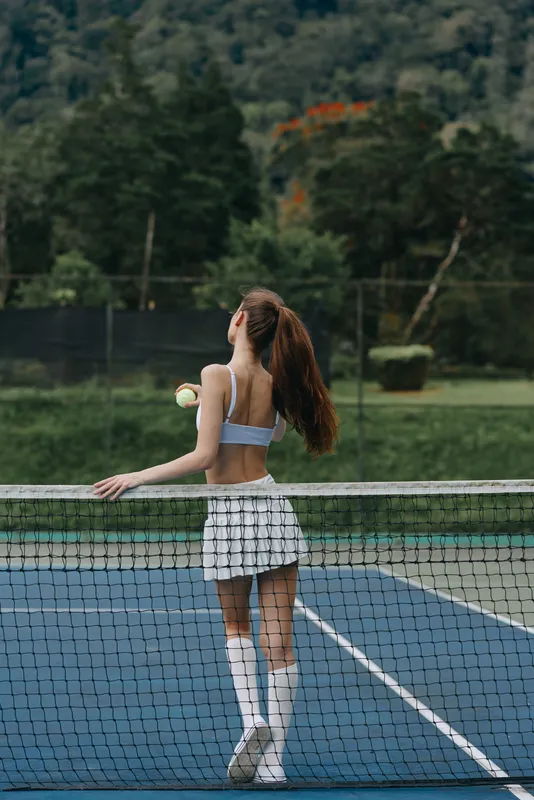 Young woman in a sporty outfit, playing tennis on a sunny day, showcasing athleticism and grace on a beautiful blue court