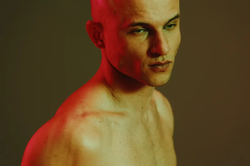 Profile of a man with a contemplative expression, illuminated by soft red light. This image captures a moody, artistic vibe in a minimalistic setting.