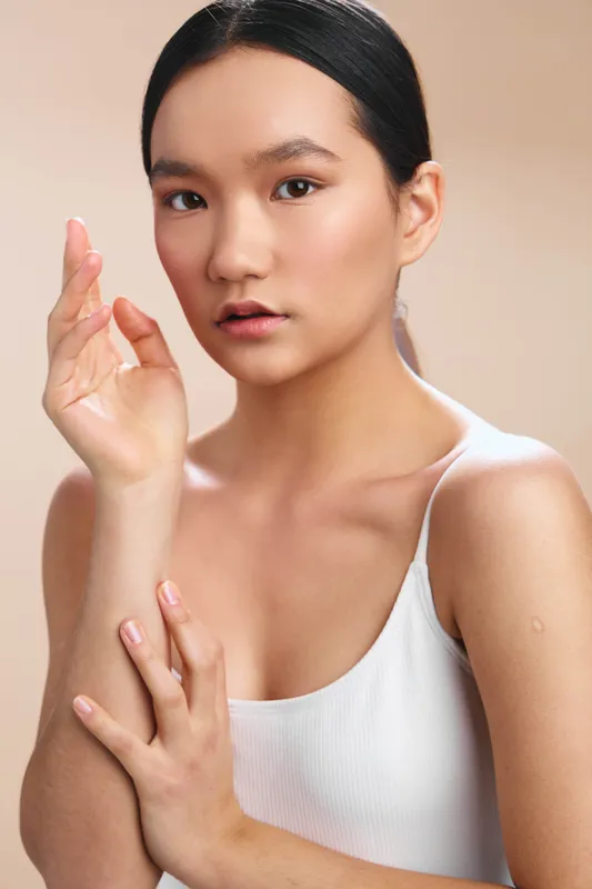 asian woman portrait in a clean studio with soft, warm lighting, calm expression, and subtle makeup highlight natural features, creating an elegant and focused mood.