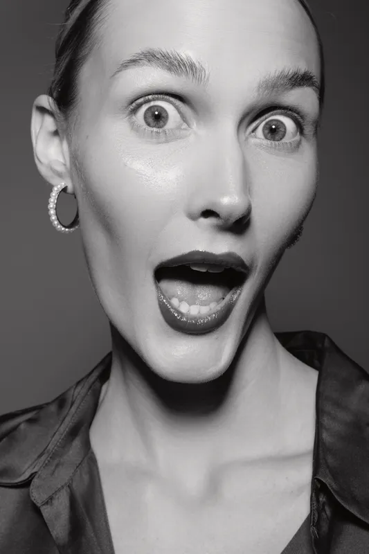 Surprised Caucasian woman with light skin and earrings looks shocked with open mouth. Black and white portrait with dramatic expression.