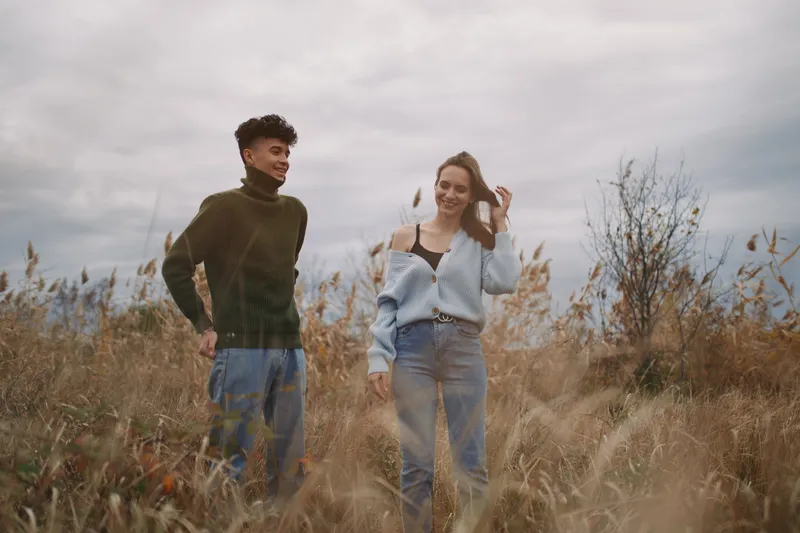 A candid outdoor moment captures authenticity and credibility as two individuals share a relaxed pose, natural gaze, and subtle smiles in a sunlit field.