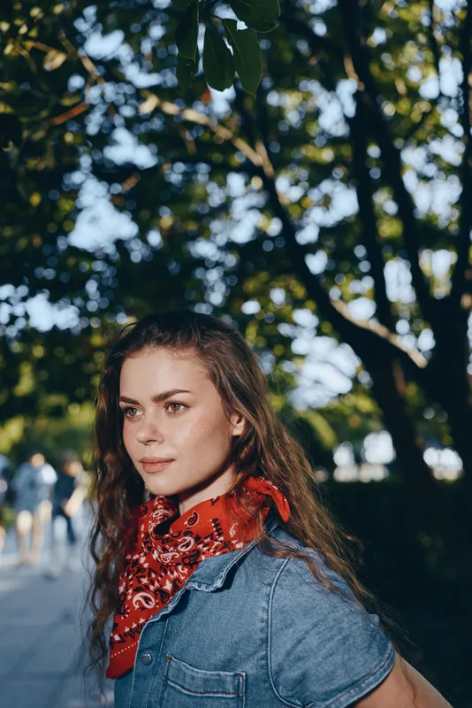 lifestyle woman in modern boho-western denim street style with a red bandana, natural light, film color tones, summer outdoors, casual fashion expression