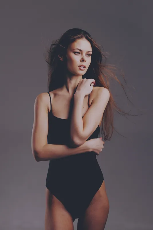 Portrait of a young woman in black bodysuit with long hair posing with thoughtful expression