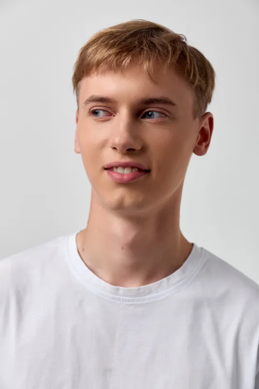 Young man in a white tee poses with a calm gaze, casual studio setting, soft lighting, and a clean, approachable mood for lifestyle and fashion imagery
