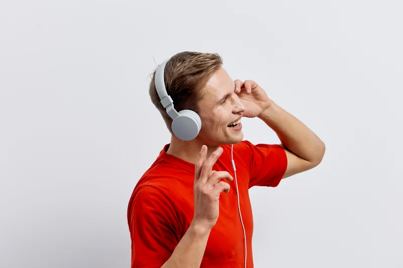 smiling young caucasian man wear red sweater white headphones listen music enjoy digital detox isolated on white background lifestyle concept