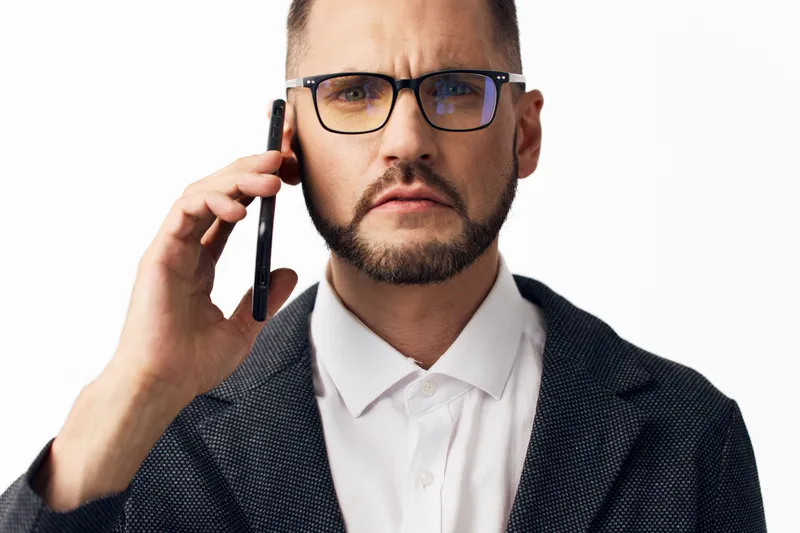 A professional man on an isolated colored background, captured during a business call, conveying confident focus and calm determination with a poised, executive demeanor in a corporate setting.