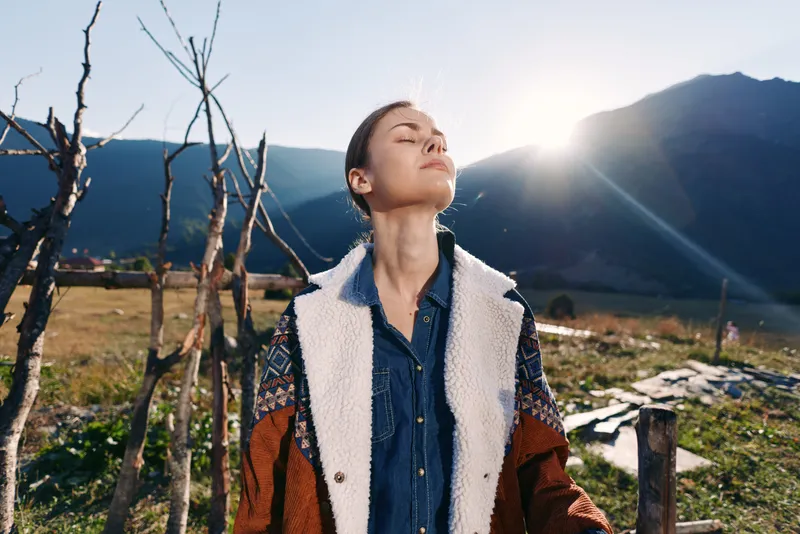 woman outdoors mountains sunlight nature portrait rural jacket traveler relaxation, portrait of a relaxed young woman in a denim shirt and warm jacket breathing fresh mountain air