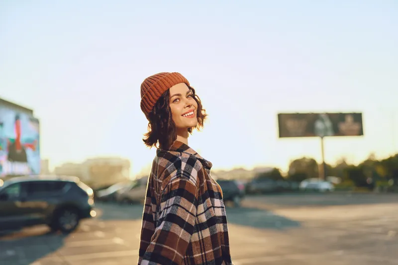 woman smile urban golden candid beanie coat outdoors lifestyle portrait happiness sunlight evening fashion cozy plaid. Authenticity, candid lifestyle and golden hour glow frame mindful living and