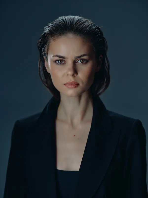 serious woman portrait with slicked-back hair wearing black jacket close-up dark background
