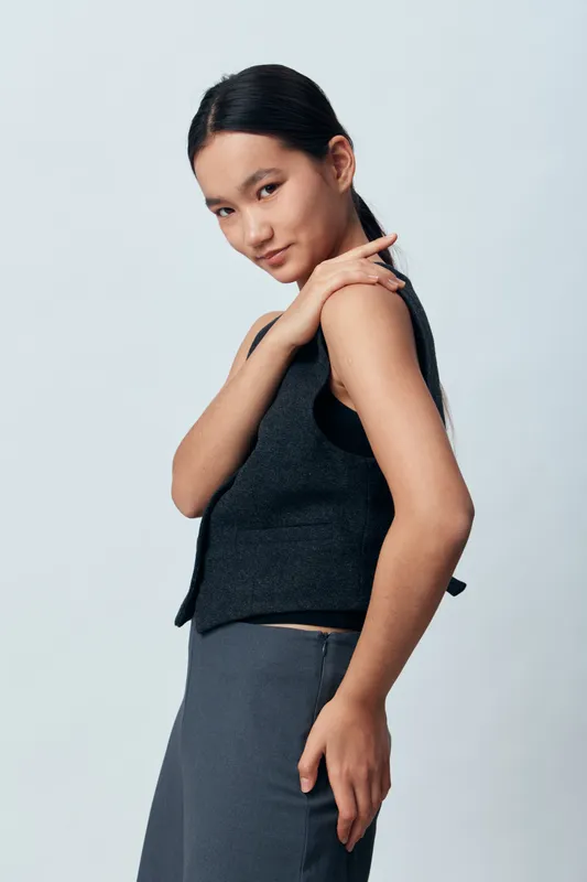 Woman posing in sleeveless top and skirt studio portrait with natural makeup and sleek hairstyle casual fashion and confidence in minimalistic clothing and simple background.