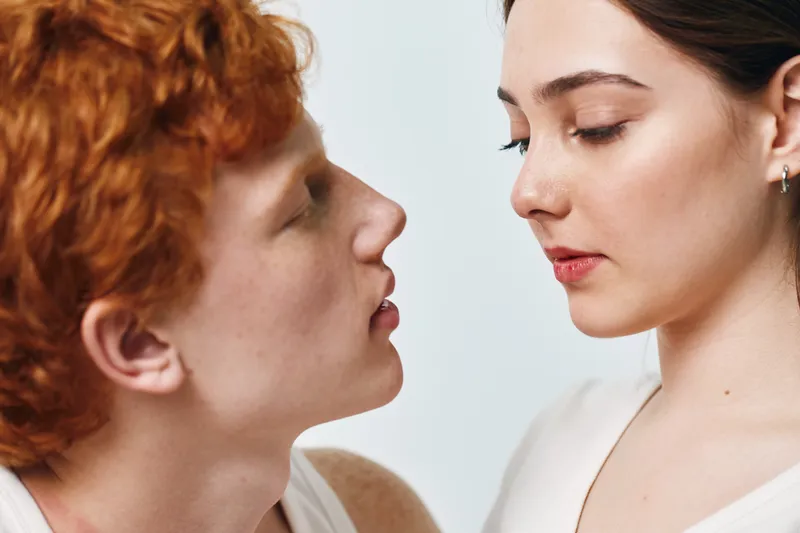 Young man and woman close together with eyes closed in intimate moment, facial expressions showing tenderness and connection between two people indoors.