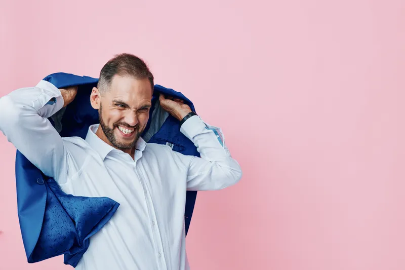 A business professional man on a solid colored background, isolated and bold. He adjusts his suit jacket, projecting confidence, focus, and determination with a strong, engaging expression.