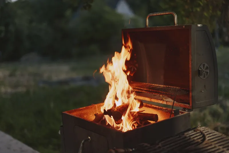 BBQ grill with flames in a backyard setting, showcasing summer cooking, outdoor dining, and vibrant fire colors, perfect for gatherings and barbecues