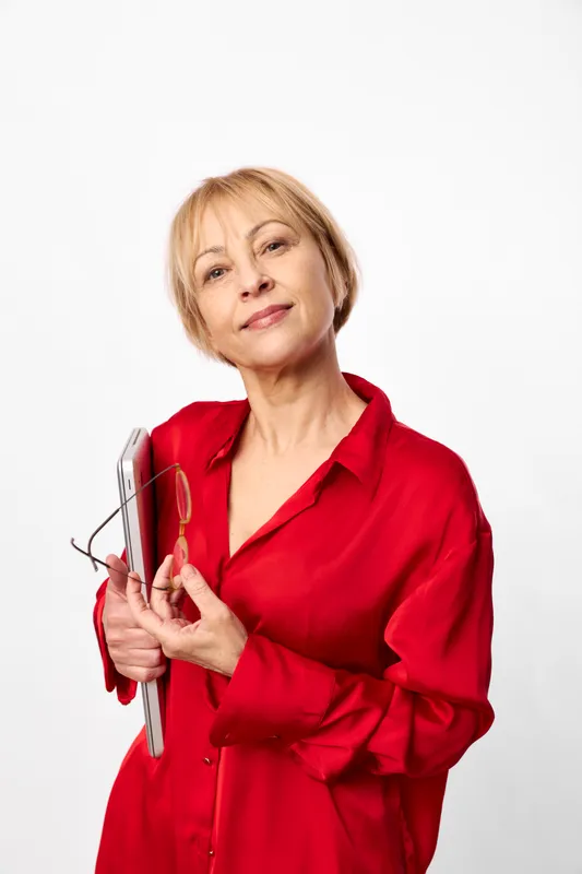 Woman hair styling iron beauty grooming red studio white background, mature woman in red shirt holds an electric hair tool, looking confident in soft studio light, selfcare routine