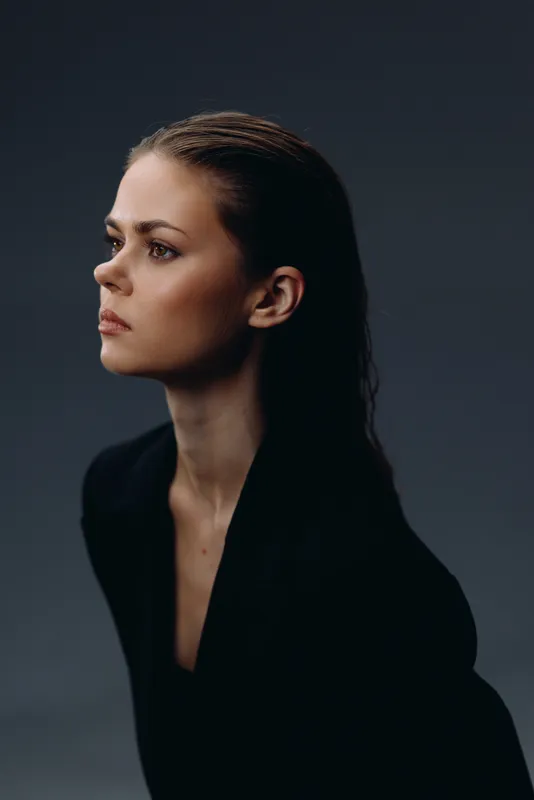 thoughtful woman portrait with dramatic lighting and dark background, showing elegance and calm mood