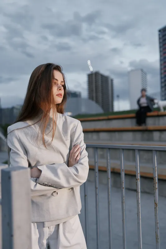 Confident businesswoman in elegant attire standing against an urban backdrop, exuding determination and professionalism.